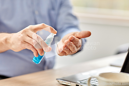 Image of man using hand sanitizer at home office