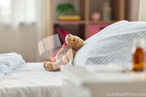 Image of teddy bear toy in bed and medicine at home