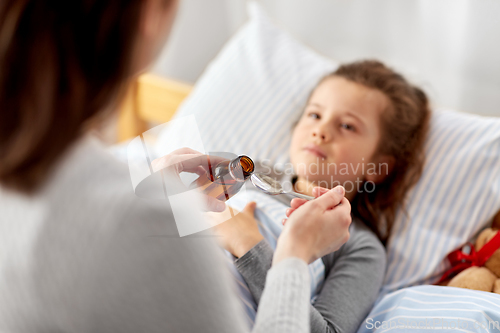 Image of mother pouring cough syrup for sick daughter