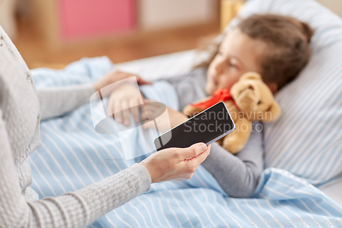 Image of sick daughter and mother with phone at home