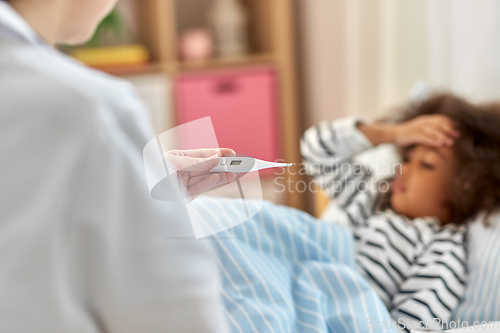 Image of doctor measuring sick girl's temperature