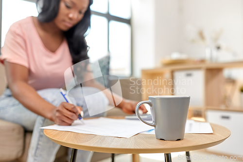 Image of african woman with papers and calculator at home