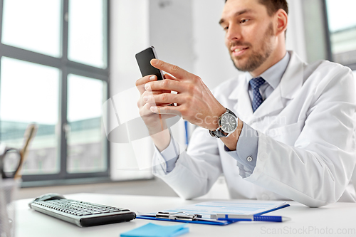 Image of smiling male doctor with smartphone at hospital