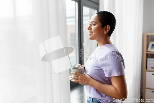 Image of happy woman with coffee looking out of window