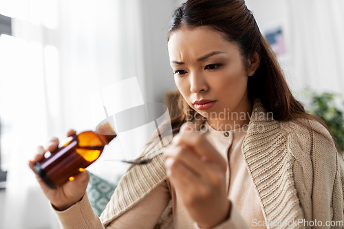 Image of sick asian woman taking medicine at home