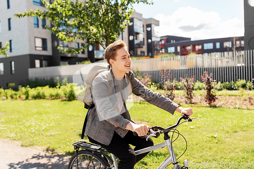 Image of smiling young man riding bicycle on city street
