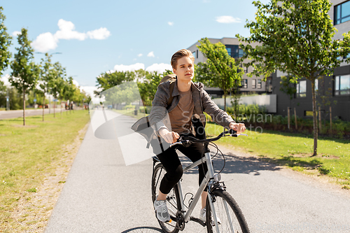 Image of young man riding bicycle on city street