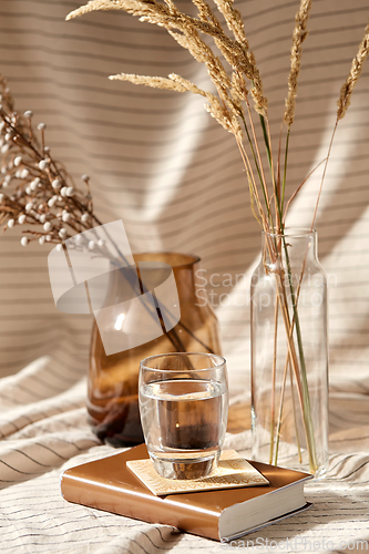 Image of glass of water, decorative dried flowers in vases