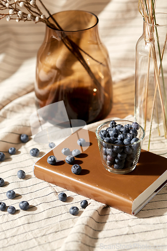 Image of cup of blueberry, book and dried flowers in vases