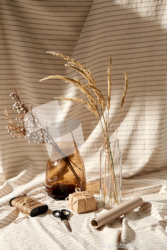 Image of gift wrapping, dried flowers in vases on drapery