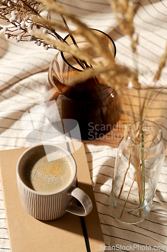 Image of cup of coffee, diary and dried flowers in vases