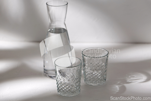 Image of two glasses and jug with water on white background