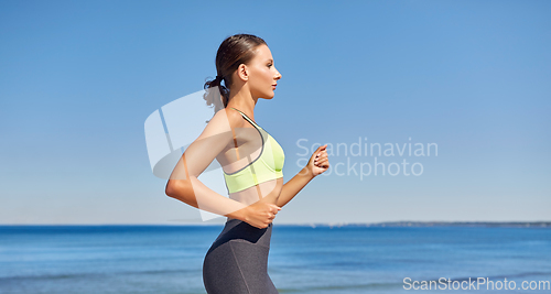 Image of young woman running along sea promenade