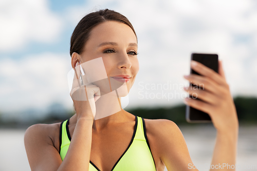 Image of woman with earphones and smartphone doing sports