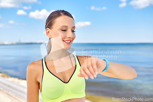 Image of smiling young woman with fitness tracker outdoors