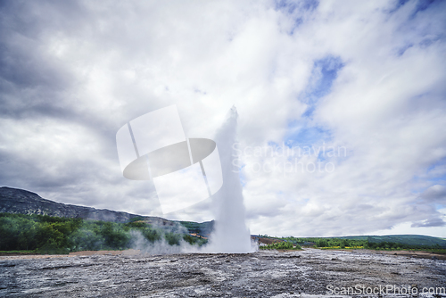 Image of Large geyser on Iceland surrounded by lava cliffs
