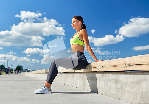 Image of happy young woman doing sports on sea promenade