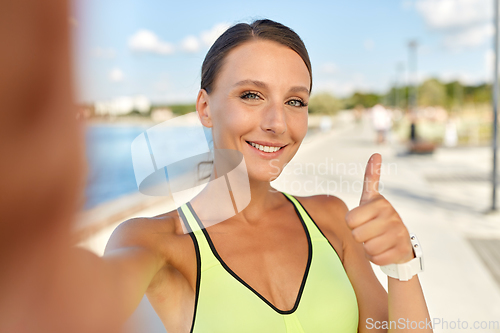 Image of sporty woman taking selfie and showing thumbs up