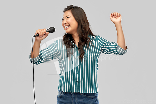 Image of happy asian woman with microphone singing
