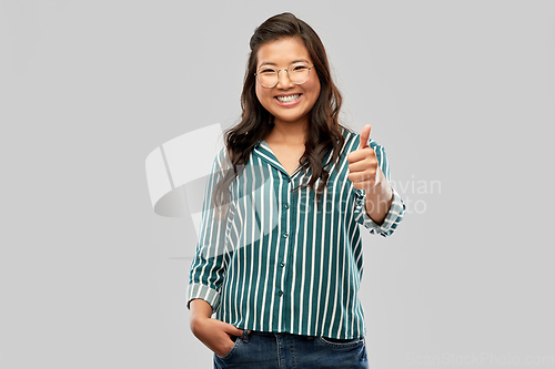 Image of happy asian woman in glasses showing thumbs up