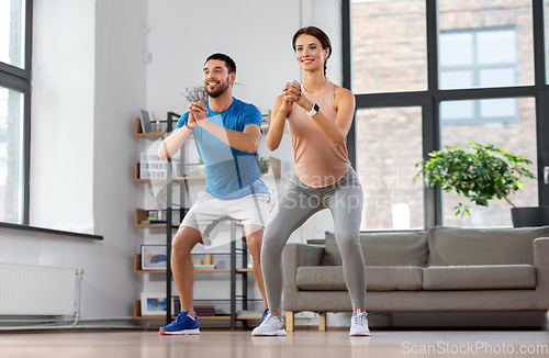 Image of happy couple exercising and doing squats at home