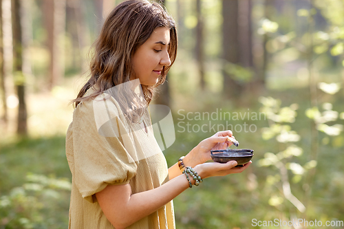 Image of woman or witch performing magic ritual in forest