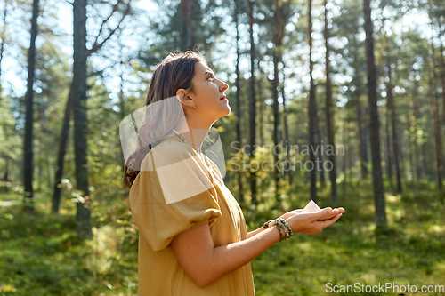 Image of young woman or witch holding pyramid in forest