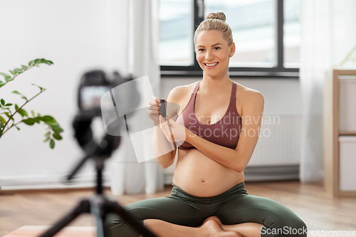 Image of pregnant woman or yoga blogger with camera at home