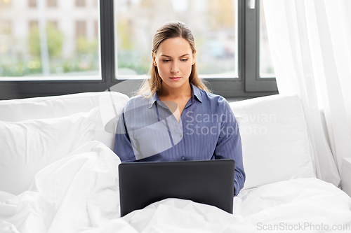 Image of young woman with laptop in bed at home bedroom