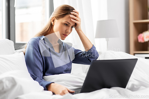 Image of stressed young woman with laptop in bed at home