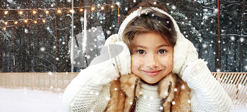 Image of girl in earmuffs at ice skating rink in winter