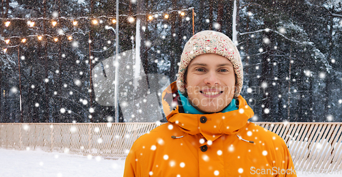 Image of happy young man at ice skating rink in winter