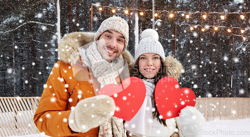 Image of happy couple with red hearts at ice rink in winter