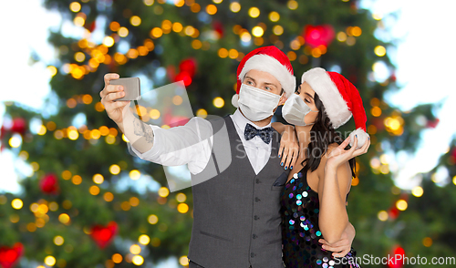 Image of couple in medical masks taking selfie on christmas