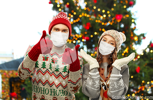 Image of couple in protective masks and christmas sweaters