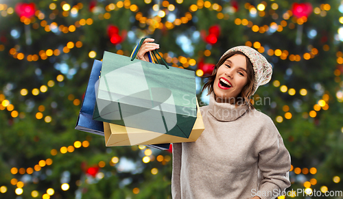 Image of happy woman with shopping bags over christmas tree