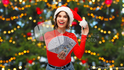 Image of happy woman in santa hat with money on christmas