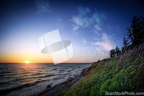 Image of Sunset by the ocean coast under a blue sky