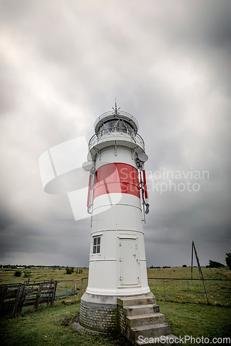 Image of Small lighthouse on a green field in cloudy weather