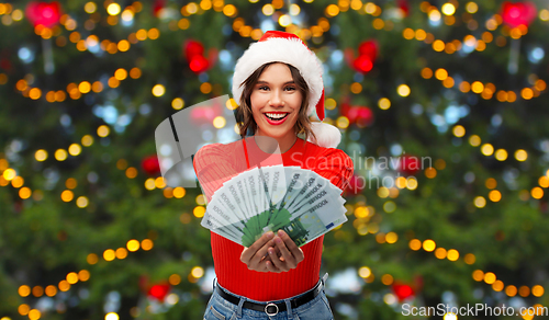 Image of happy woman in santa hat with money on christmas
