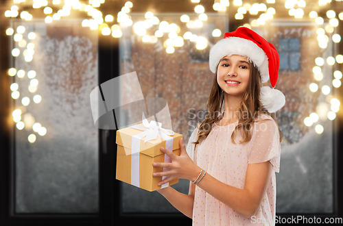 Image of teenage girl in santa hat with christmas gift