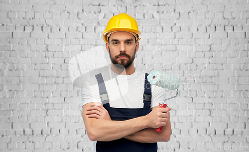 Image of male builder with paint roller over brick wall