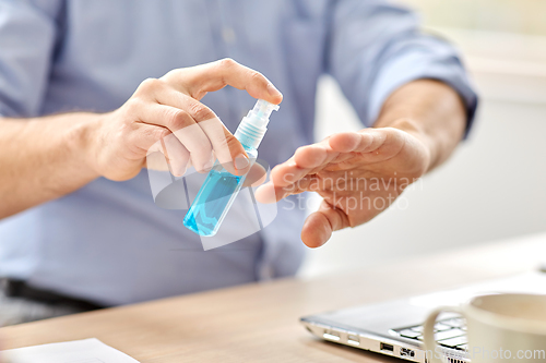 Image of man using hand sanitizer at home office