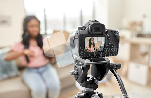 Image of female video blogger with camera and box at home