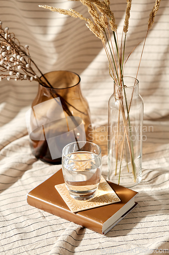 Image of glass of water, decorative dried flowers in vases