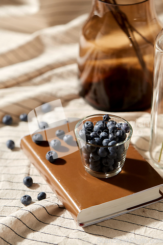 Image of cup of blueberry, book and dried flowers in vases