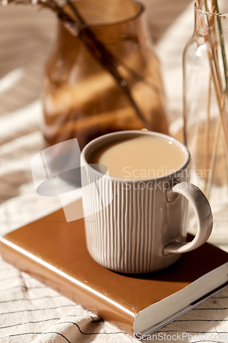 Image of cup of coffee on book and dried flowers in vases