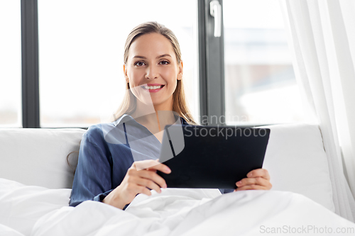 Image of young woman with tablet pc in bed at home bedroom