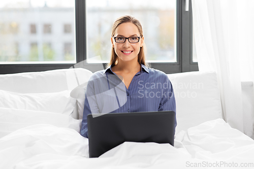 Image of young woman with laptop in bed at home bedroom