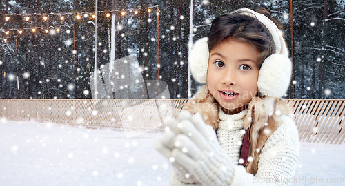 Image of girl in earmuffs at ice skating rink in winter